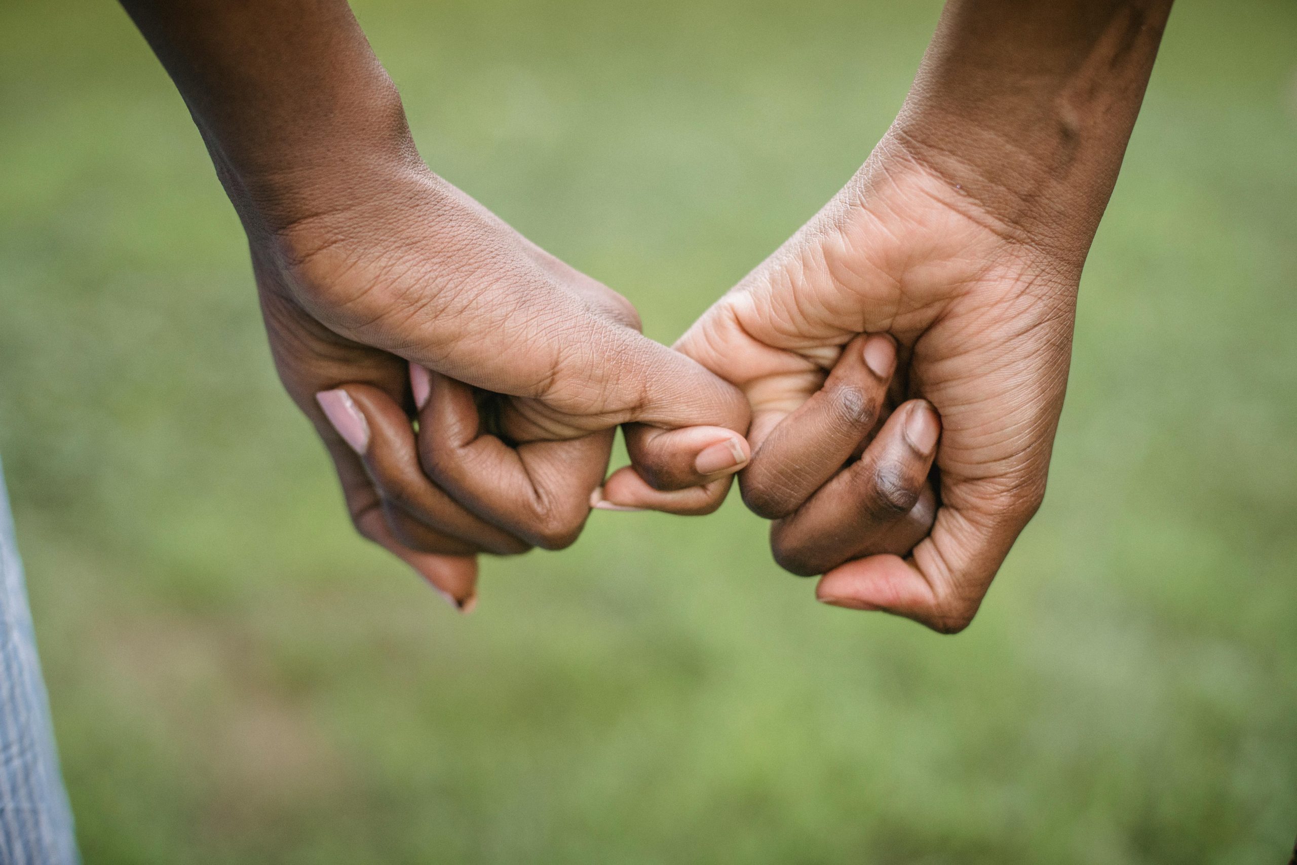 A touching moment as a couple holds hands with a green backdrop, symbolizing unity and connection.